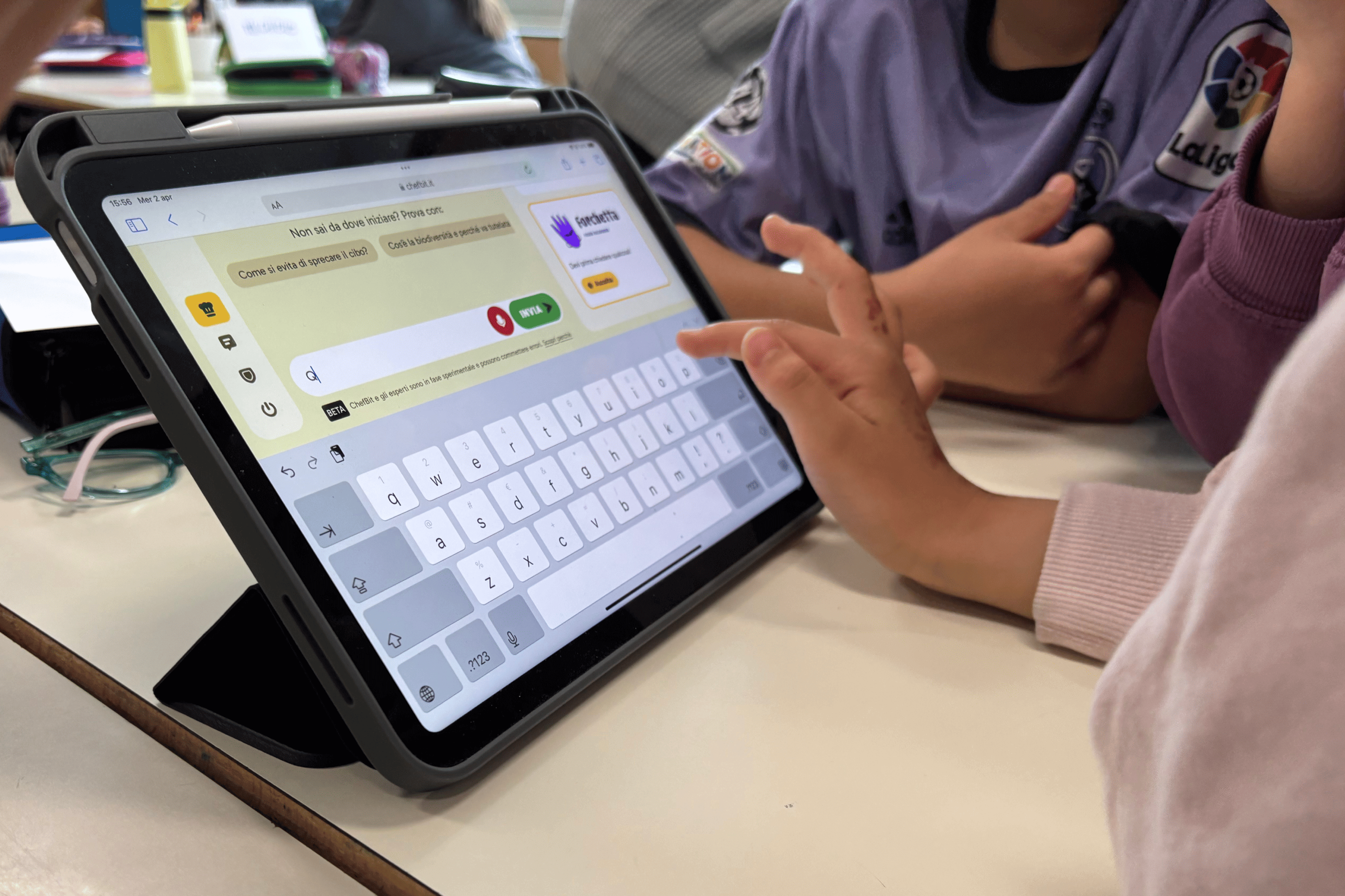 Bambini usano un tablet digitando su una tastiera virtuale nell’app Chef Bit, impegnati a interagire con domande educative e attività digitali.